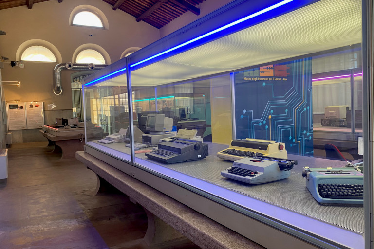 La vitrine contient plusieurs machines à écrire des marques Olivetti et Underwood, et des ordinateurs des marques Olivetti, Apple et NeXT.